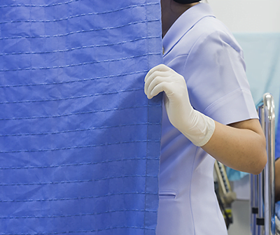 Nurse with gloved hand pulls a hospital curtain