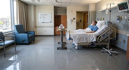 Woman in hospital bed.  Clean shiny floors.